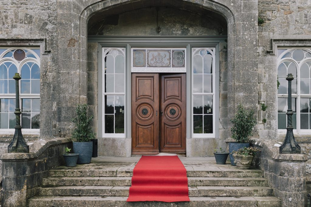 Slane Castle in Ireland front brown wooden door with red carpet ready for wedding ceremony