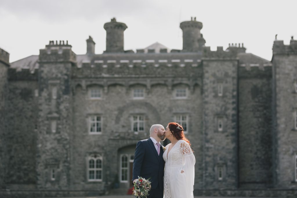 Wedding couple kissing each other in front of historical Slane Castle in co Meath Ireland on a cloudy day