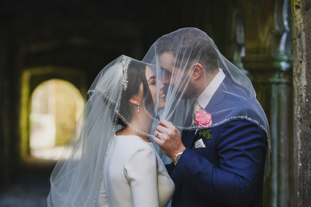wedding couple kissing each other at the bective abbey covering with a veil